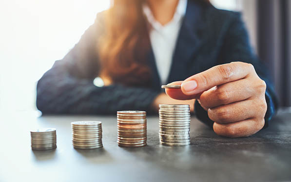 Businesswoman holding and stacking coins on the table